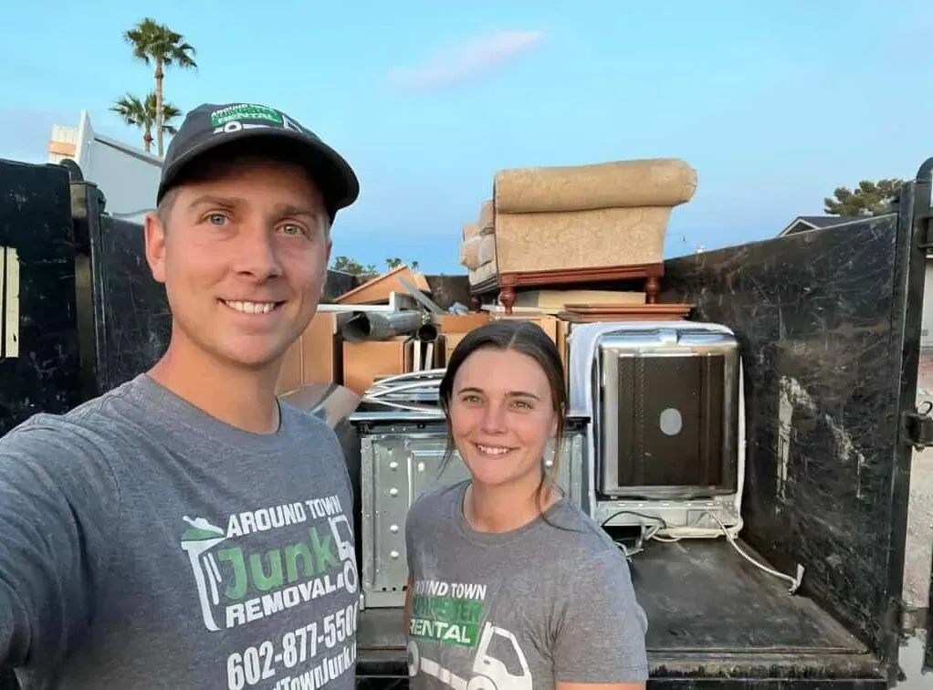 Garrett and Megan Frix beside a truck loaded with an old dishwasher, microwave and furniture