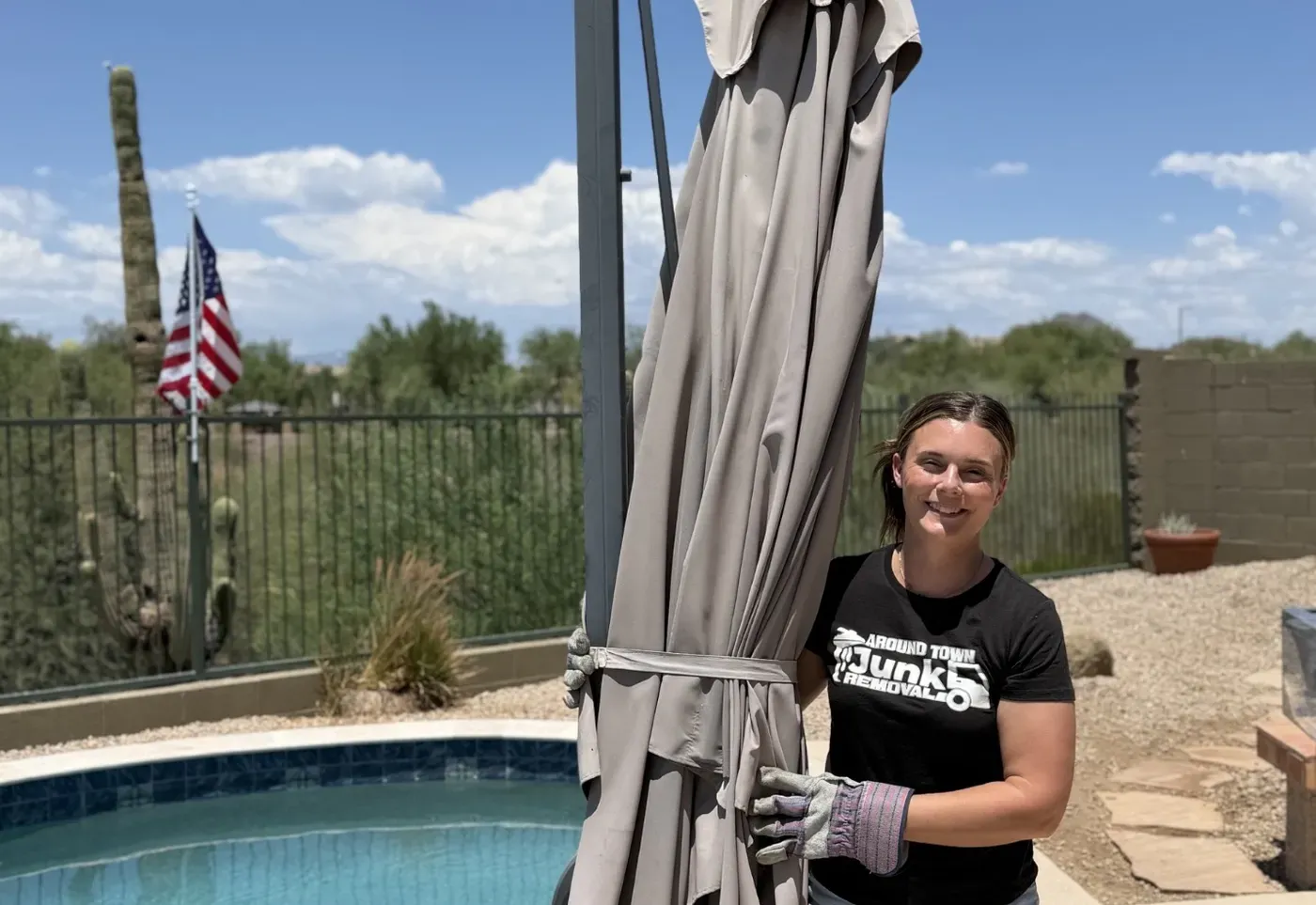 A crew member carrying a wrapped patio umbrella past a pool on a Fountain Hills job