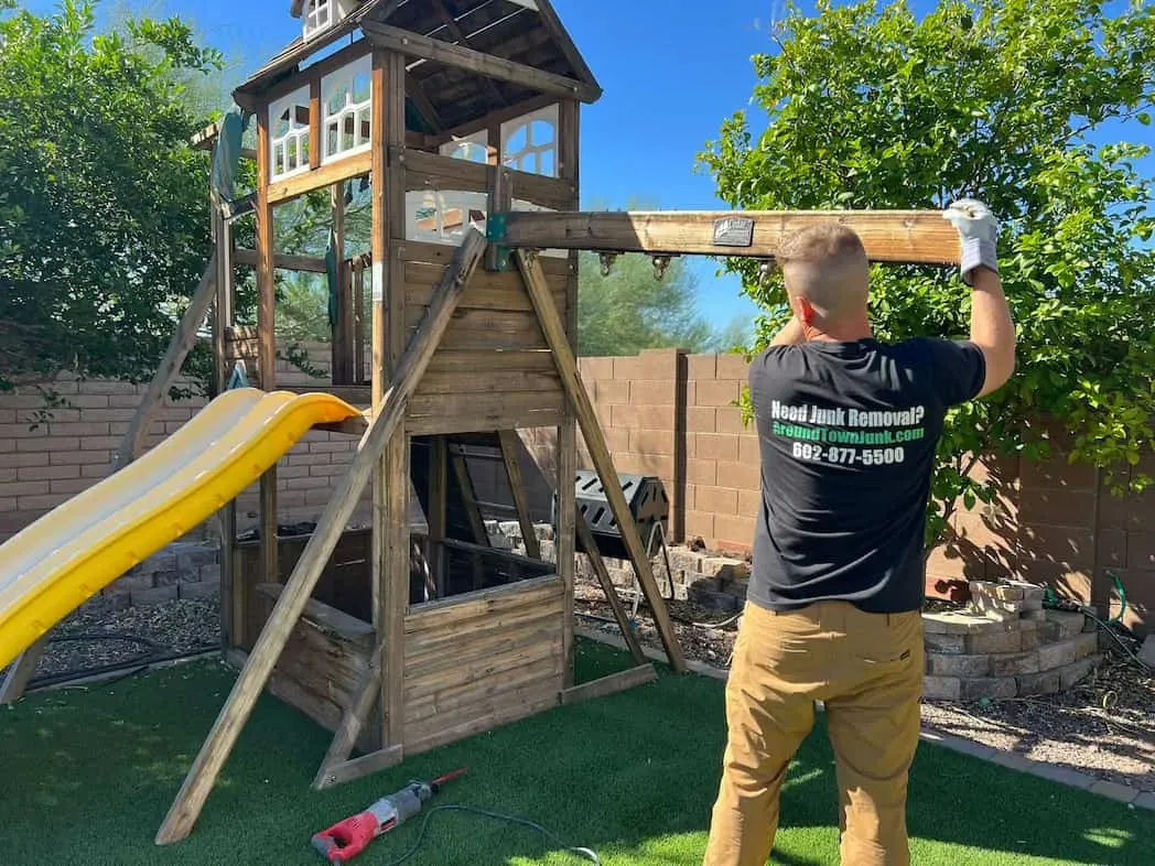 A crew member dismantling a wooden backyard playset in Gainey Ranch, Scottsdale