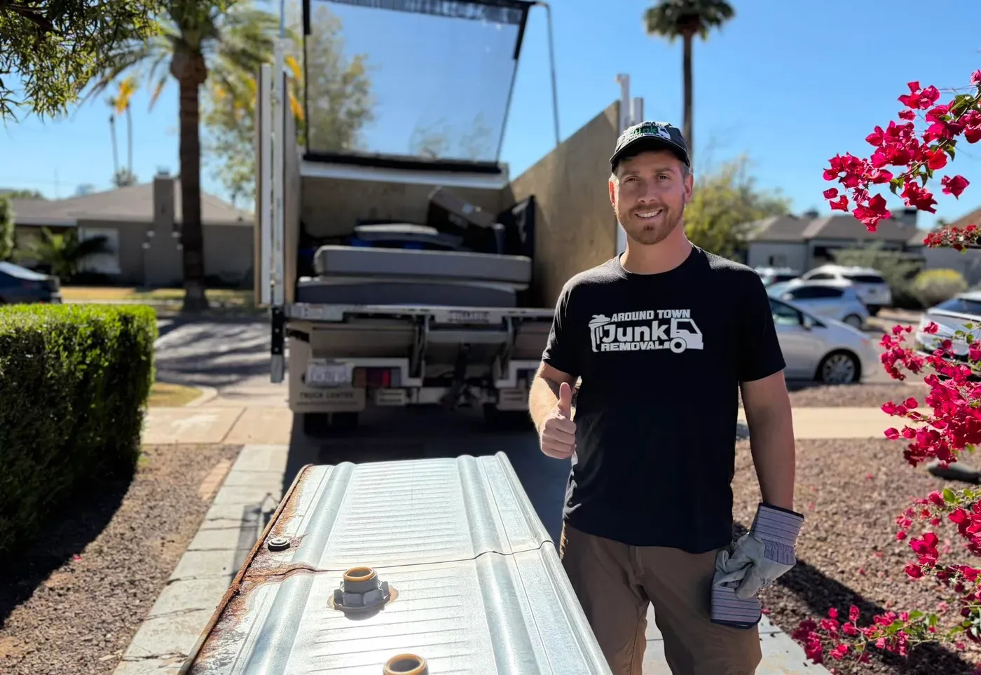 A crew member beside the truck with a deflated inflatable hot tub laid out on the lawn in Grayhawk
