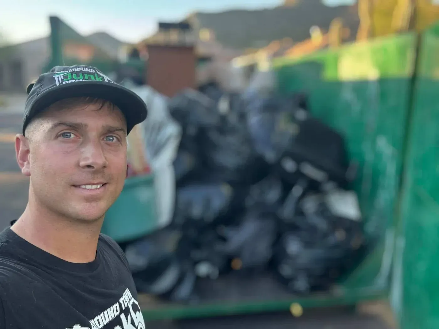 A crew member loading bagged waste into a dumpster in Old Town Scottsdale