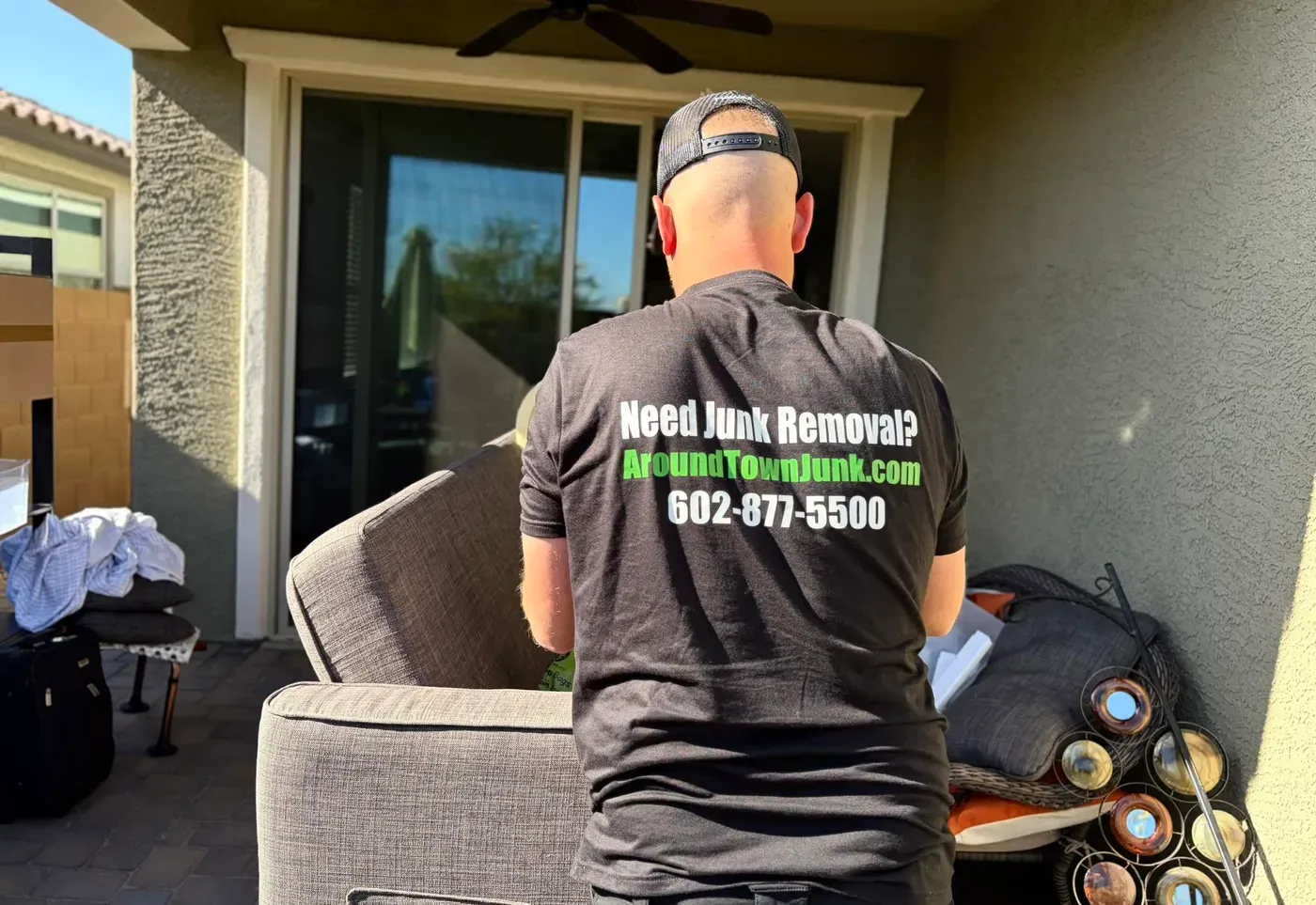 A crew member lifting patio cushions and planters outside a Peoria home