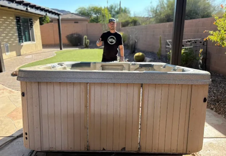A crew member behind an old hot tub being removed from a Pinnacle Peak patio