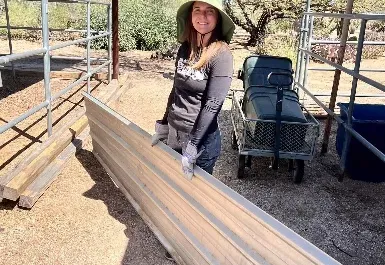 A crew member loading corrugated horse-panel fencing onto a cart in Rio Verde
