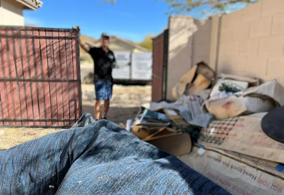 A side-yard pile of soaked cardboard and debris cleared from a Troon North rental