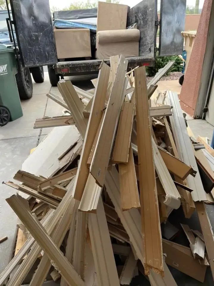 A pile of torn-out baseboard and trim on a job site driveway