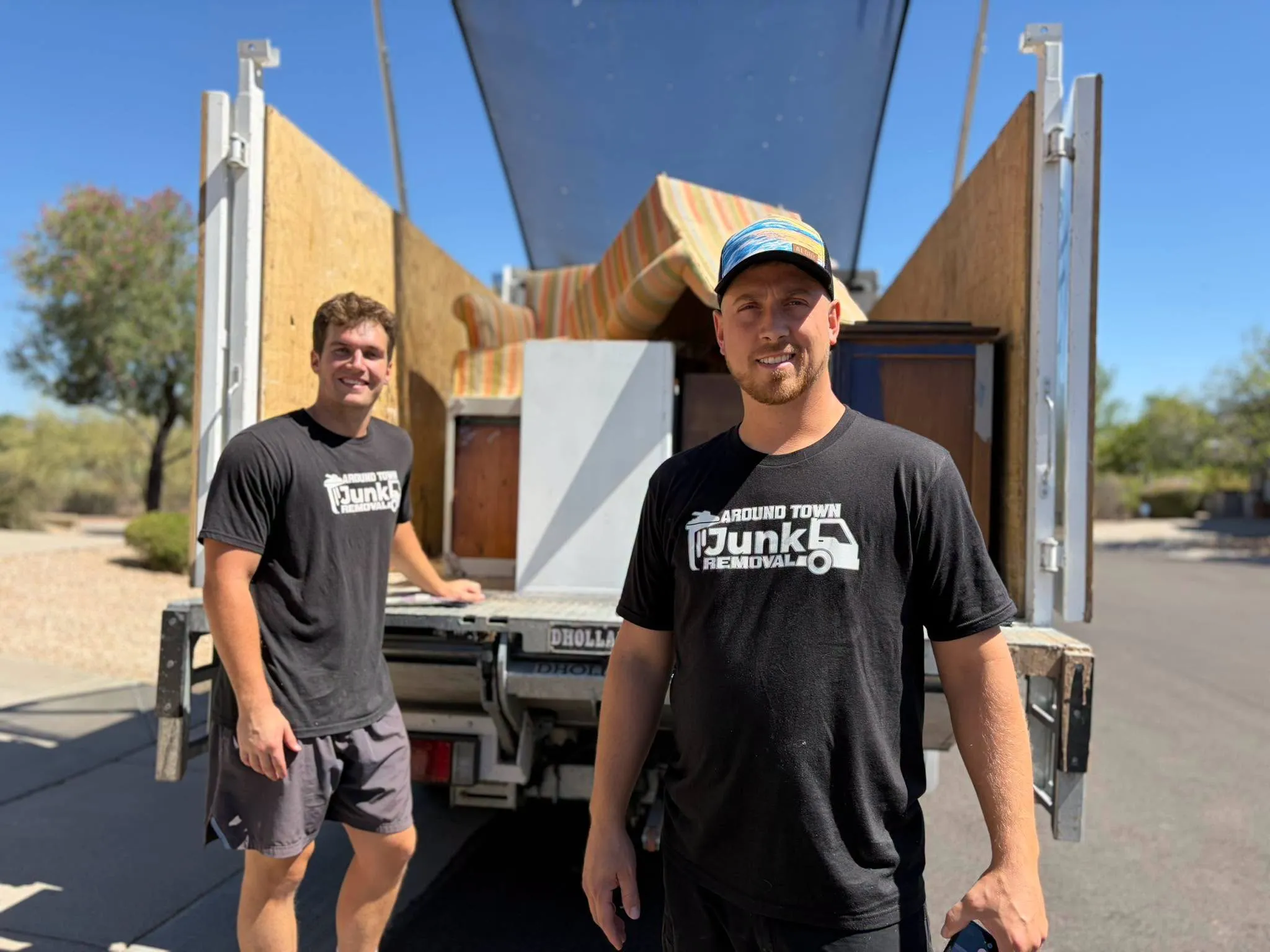 Two crew members at the back of a loaded Around Town truck