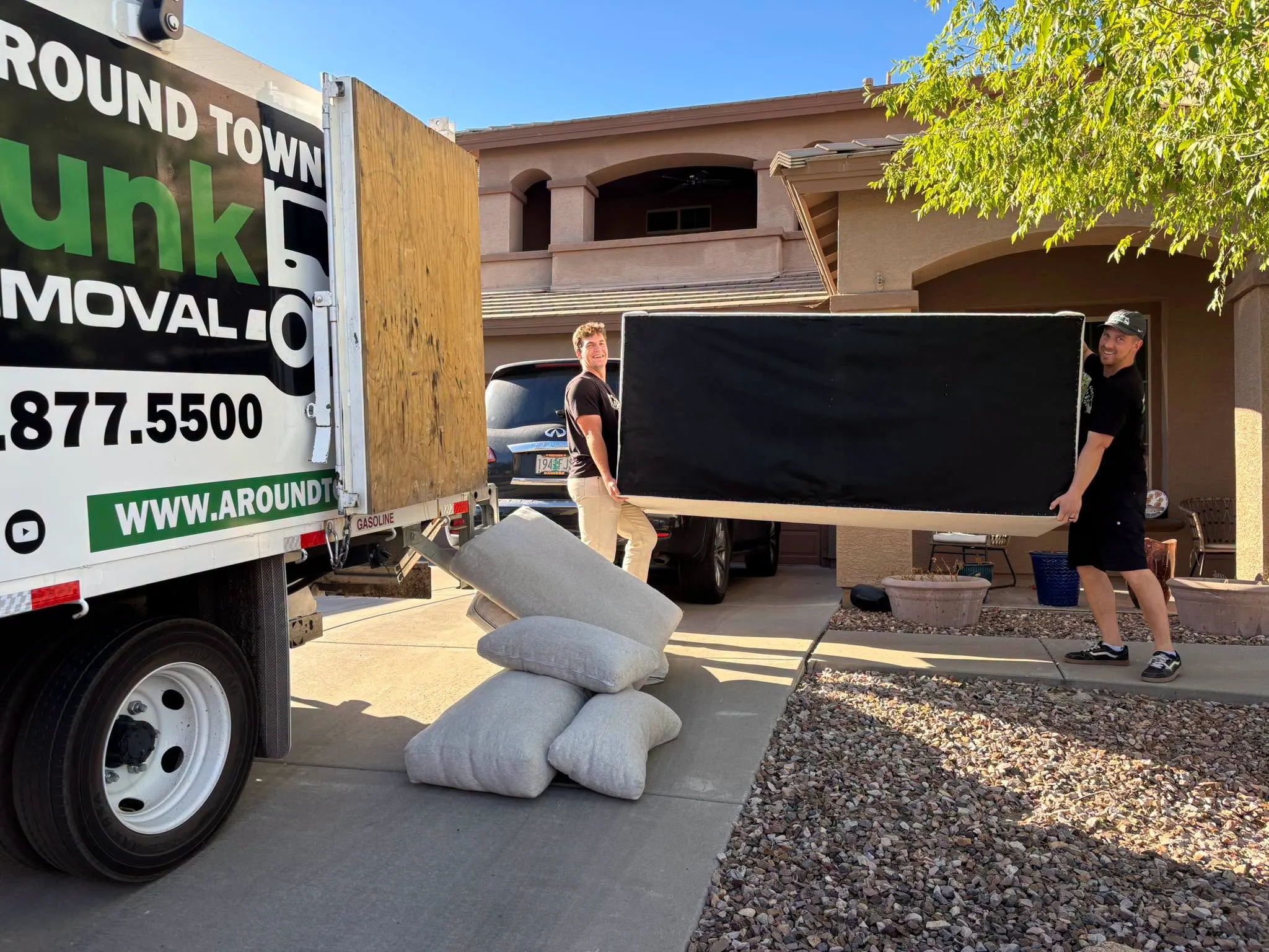 Two crew members carrying a box spring to the truck at a Phoenix home
