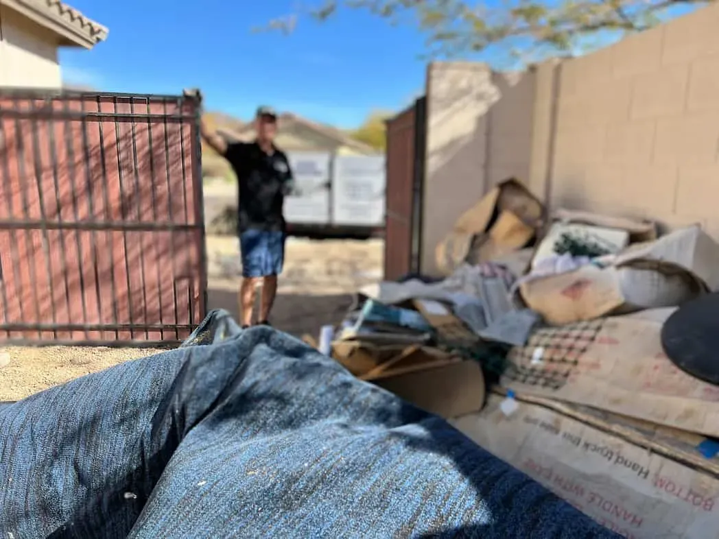 Bagged and boxed belongings sorted beside a gate during a cleanout