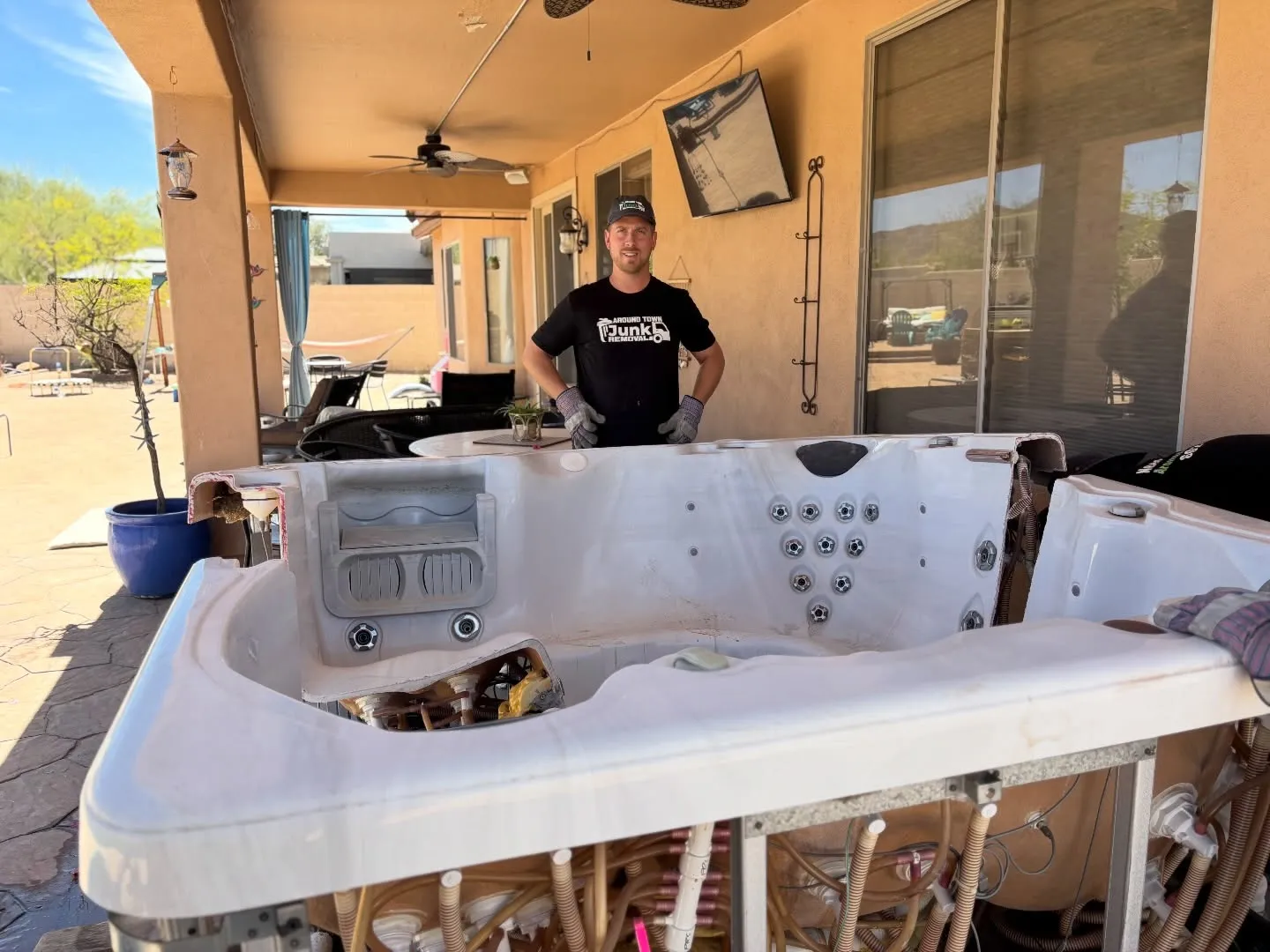 A crew member dismantling an old hot tub on a Phoenix patio